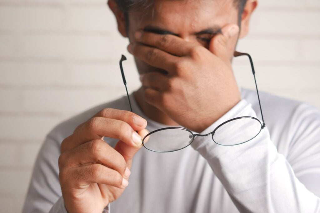 man rubbing eyes glasses