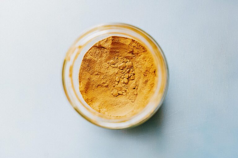 A jar filled with vibrant turmeric powder viewed from above.