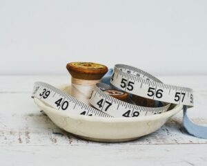 Psychology of Sustainable Weight Management.Spools and measuring tape in a decorative dish.